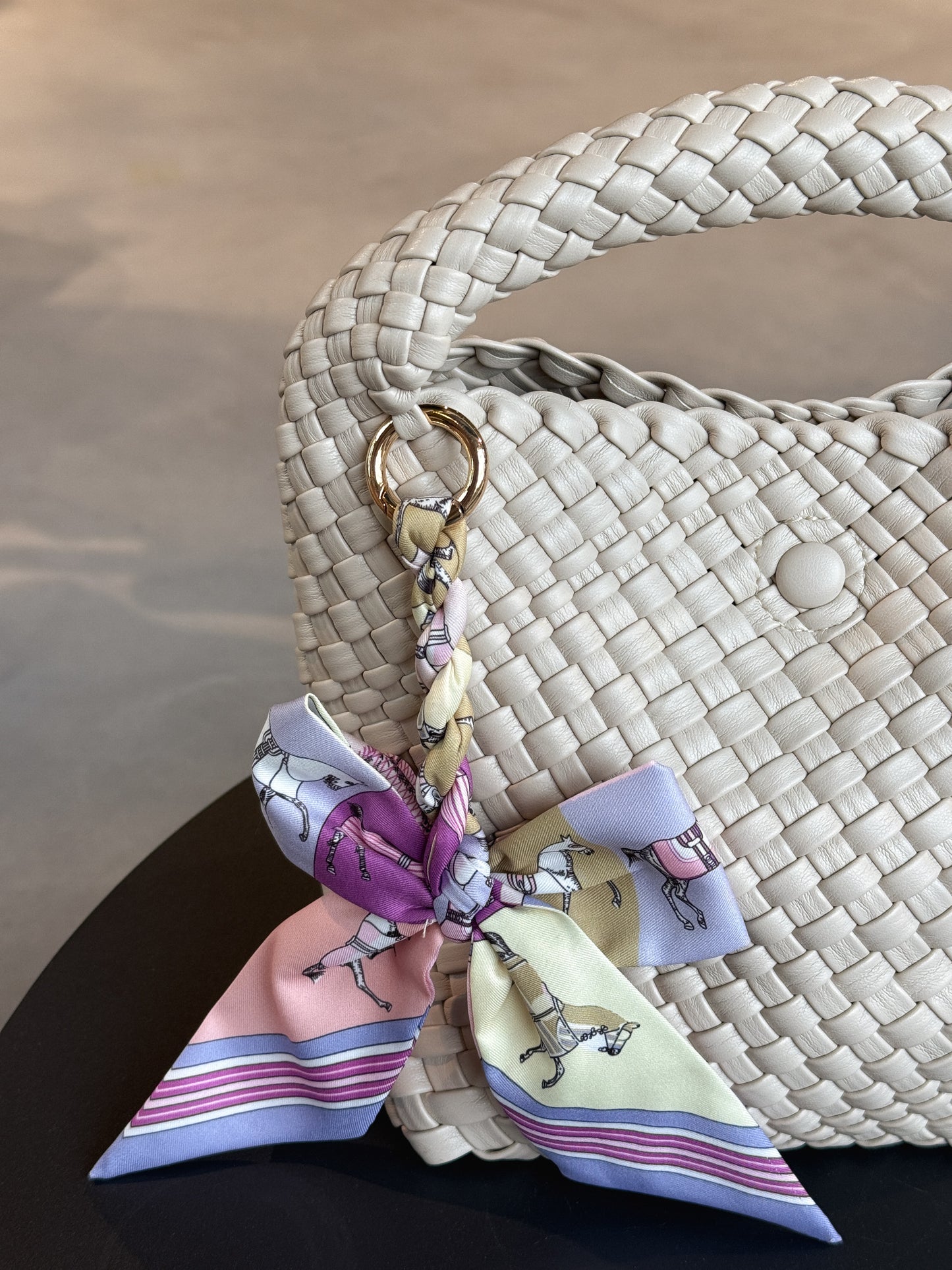 Braided Bow Charm in gedrehter Schleifenform, befestigt an einer Tasche – modischer Accessoire-Trend aus Twill in lilanem Muster