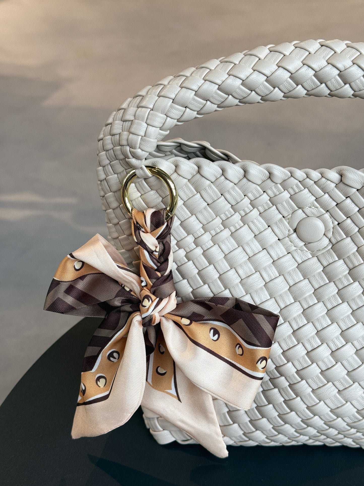 Braided Bow Charm in geflochtener Schleifenform, befestigt an einer Tasche – modischer Accessoire-Trend aus Twill in braunem Muster