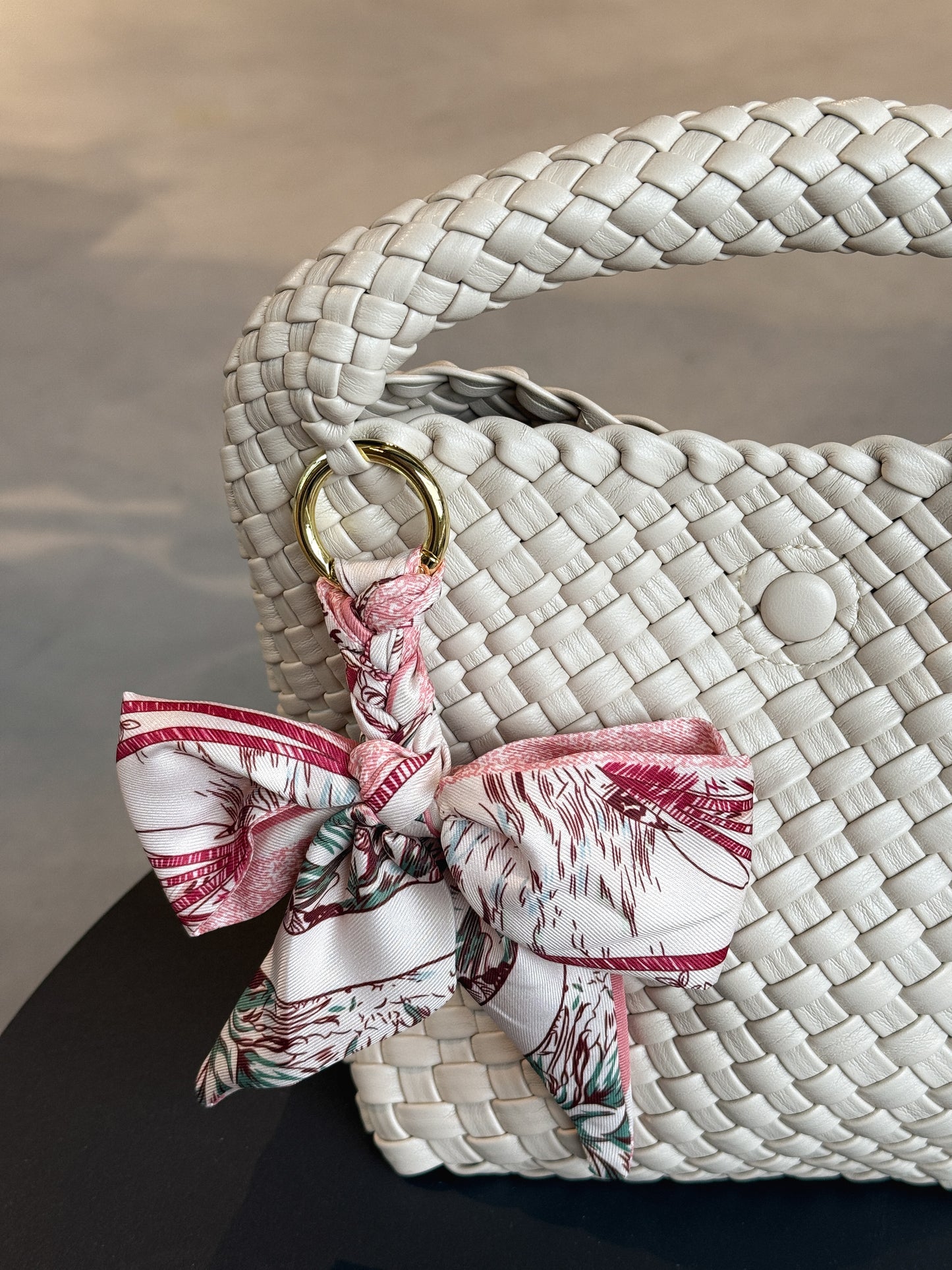 Braided Bow Charm in geflochtener Schleifenform, befestigt an einer Tasche – modischer Accessoire-Trend aus Twill in rosanem Muster