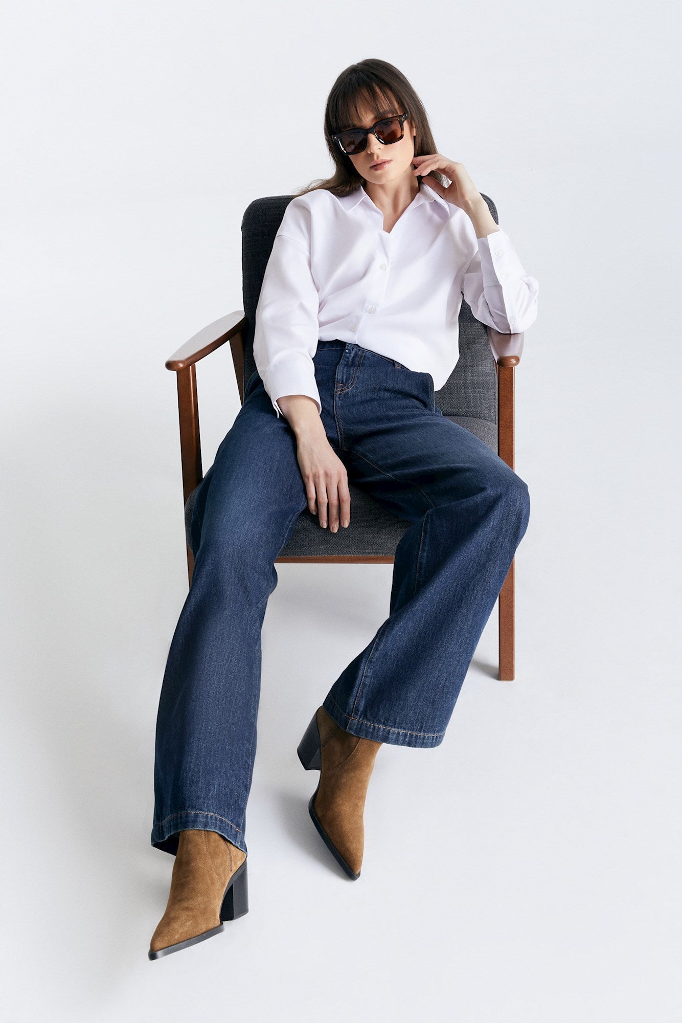 COJ Maxine Wide Leg Deep Blue Jeans, entspannt getragen mit braunen Stiefeln und weißem Hemd, sitzend.