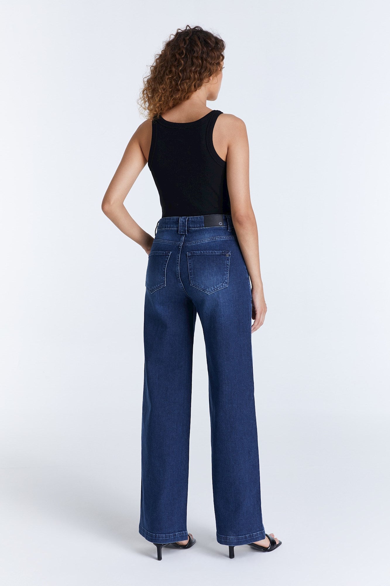 Rückansicht der COJ Lulu Wide Leg Dark Blue Jeans getragen von einer Frau. Die Jeans hat eine hohe Taille und eine lockere Passform.