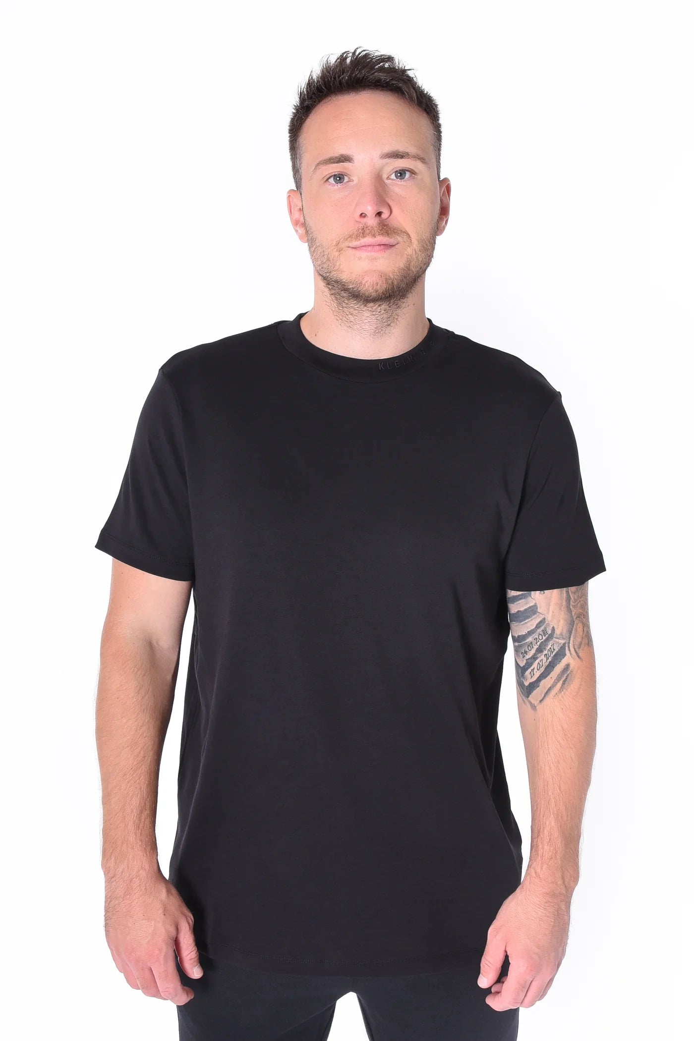 Kleinigkeit Bastian Feinsteiger schwarzes T-Shirt mit hohem Kragen, dezentem Ton-in-Ton Schriftzug und geradem Abschluss – zeitlos und stilvoll.