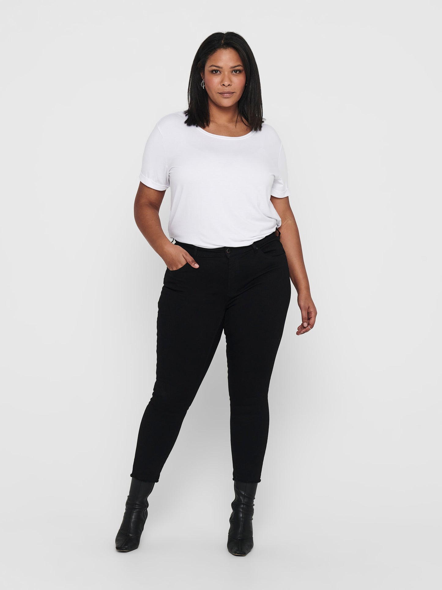Ganzkörperansicht der Only Carmakoma Carwilly Skinny Black Jeans, getragen von einem Model mit weißem Shirt und schwarzen Boots. Die schwarze Skinny Jeans kombiniert Komfort und Stil.