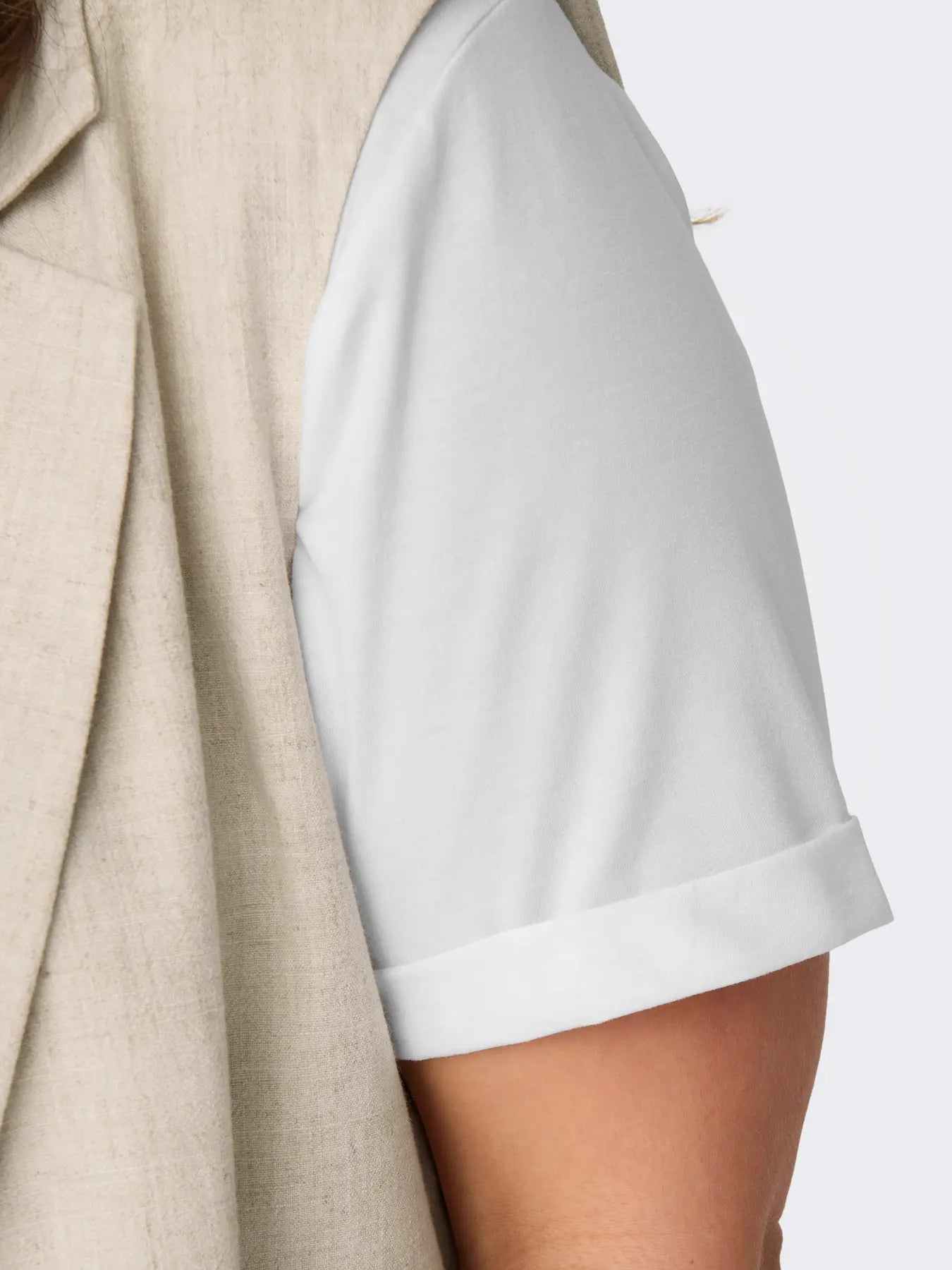 Nahaufnahme des Only Carmakoma Moster Fold Up Top White mit hochgekrempeltem Ärmel und weichem Stoff.