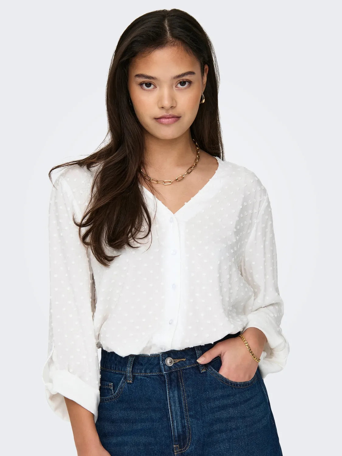 Komplettansicht eines Outfits mit einer weißen Bluse von JDY, hochgekrempelten Ärmeln und schwarzer Hose, getragen von einem lächelnden Model.