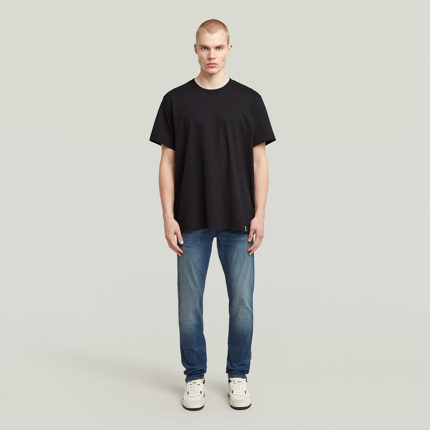 Model trägt die G-Star 3301 Slim Jeans mit mittelhohem Bund und klassischem 5-Pocket-Design, kombiniert mit einem schwarzen T-Shirt.