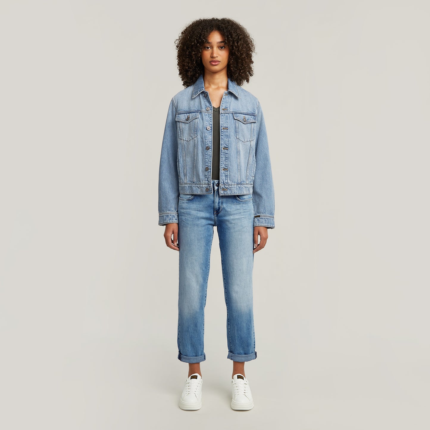 Ganzkörperansicht einer Frau, die die G-Star Kate Boyfriend Jeans in Light Indigo Aged mit hochgekrempeltem Saum und einer Jeansjacke trägt.