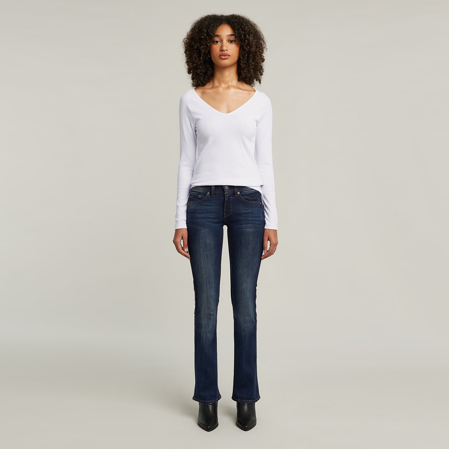 Modell trägt die G-Star Midge Bootcut Dark Aged Jeans mit figurbetontem Schnitt und dunkel gewaschenem Denim.