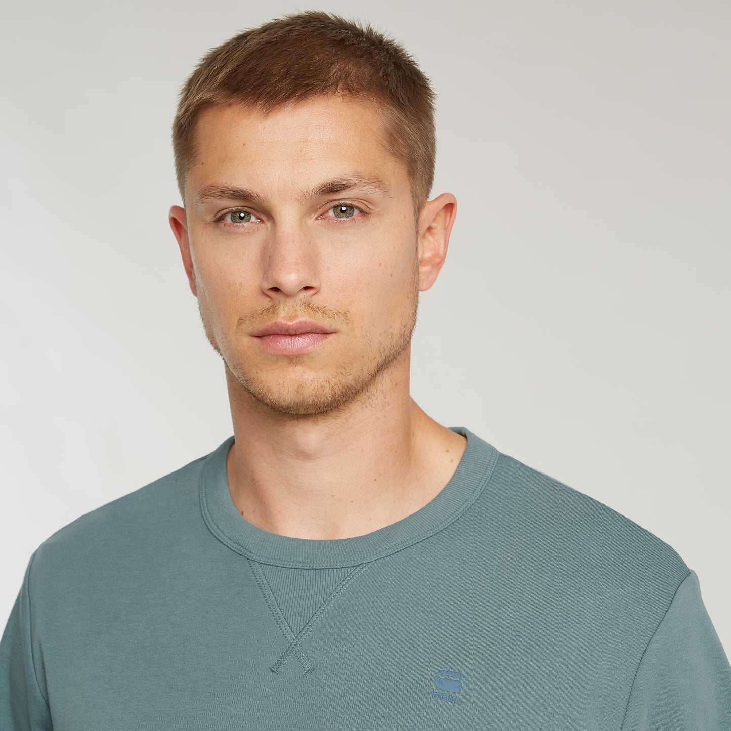 Model trägt das G-Star Nifous T-Shirt in Bolt Grey, Nahaufnahme des Gesichts und oberen Shirt-Bereichs.