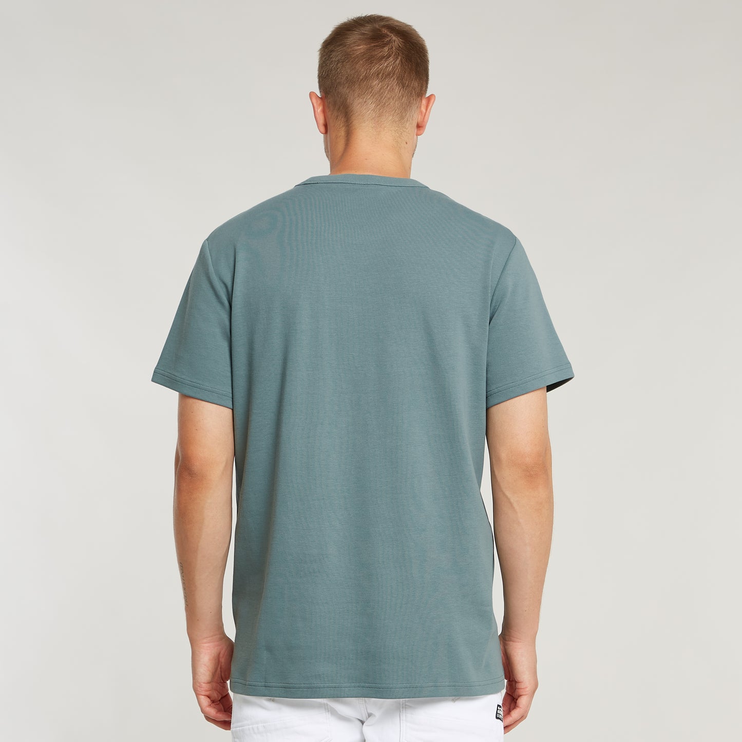 Rückansicht des G-Star Nifous T-Shirts in Bolt Grey, getragen mit einer weißen Hose.