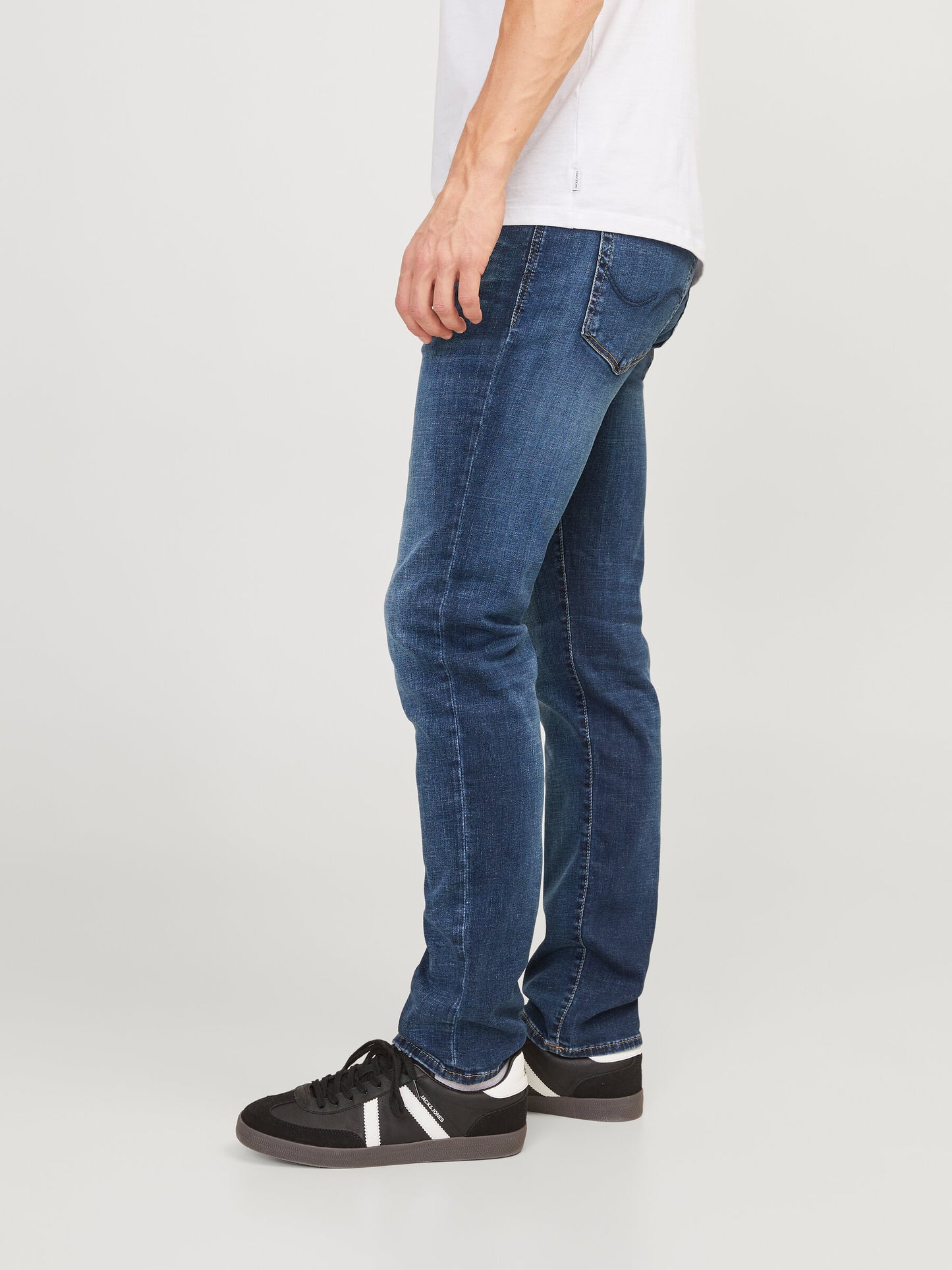Seitliche Ansicht der Jack & Jones Glenn Slim Blue Denim Jeans, getragen von einem Model mit schwarzen Sneakern.