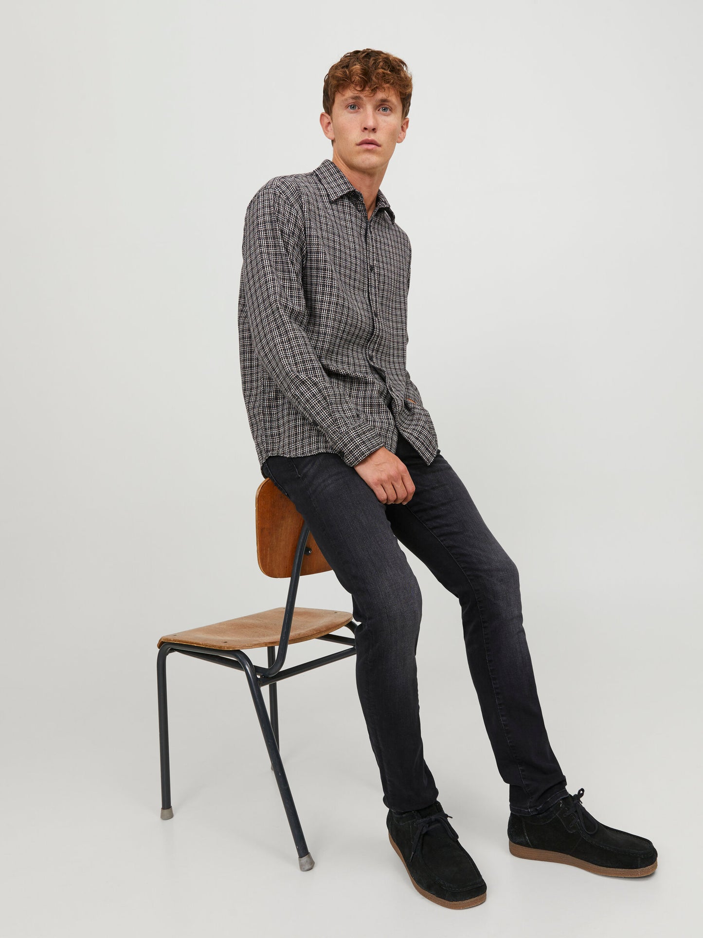 Jack & Jones Glenn Slim Black Denim in voller Ansicht, getragen von einem Model, sitzend auf einem Stuhl.
