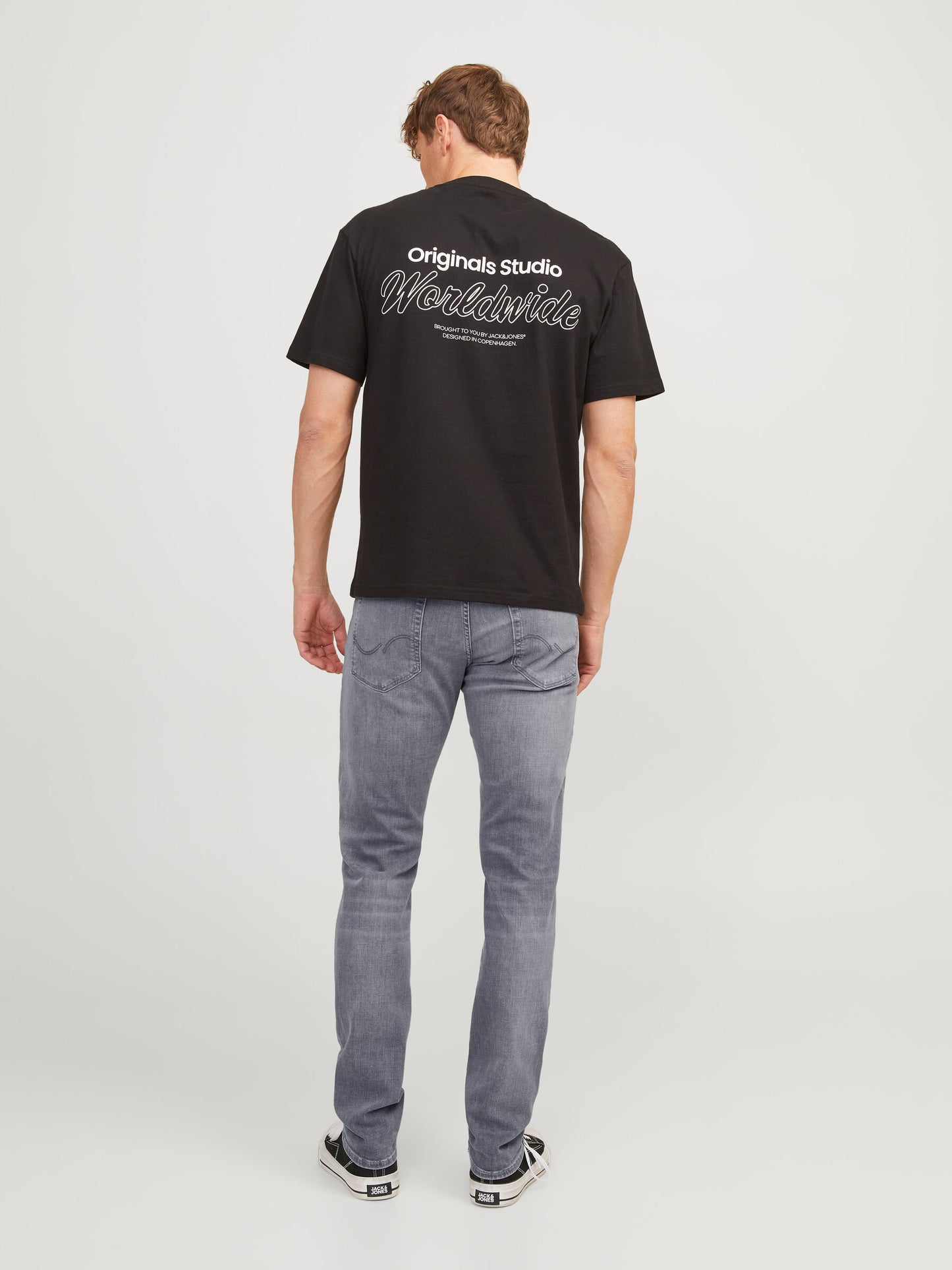 Rückansicht der Jack & Jones Glenn Slim Grey Denim kombiniert mit einem schwarzen T-Shirt und Sneakers.
