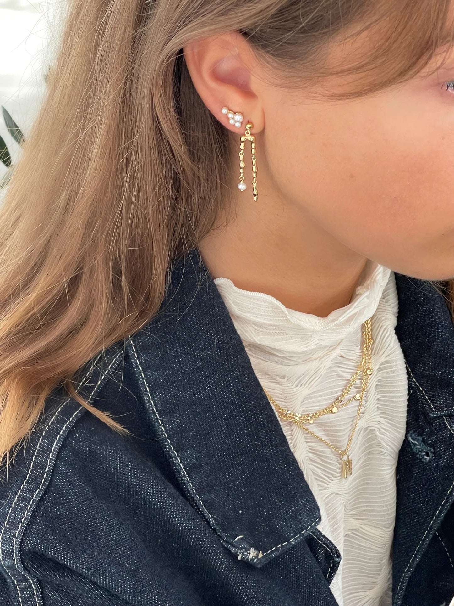 Jeberg Jewellery Harmony Pearl Double Earring getragen, kombiniert mit weiteren Ohrringen und goldenen Ketten für einen eleganten Layering-Look.