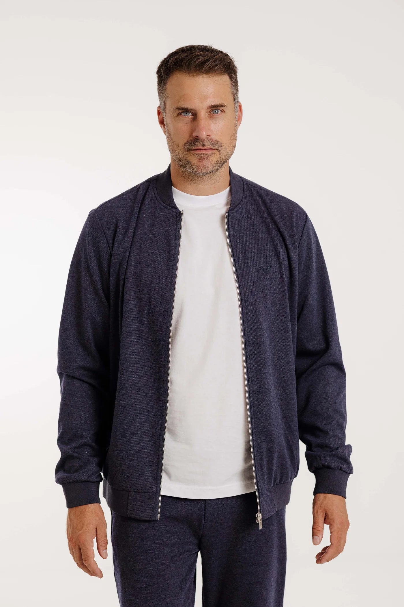 Nahaufnahme eines Mannes mit dem Kleinigkeit Peter Maffein Blouson Navy Blue, offen getragen über einem weißen T-Shirt.