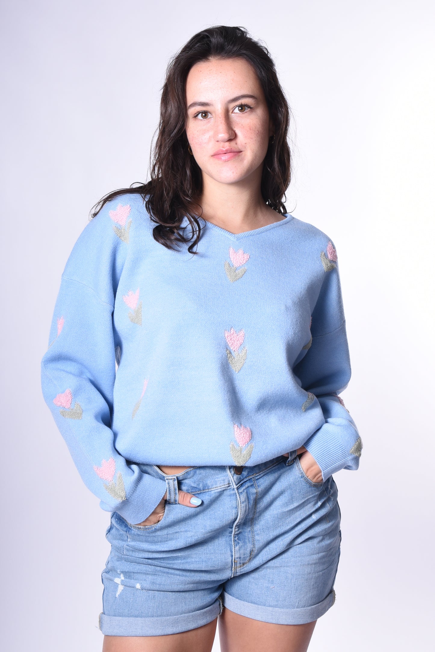 Frau trägt den Kleinigkeit Tulpen Wollma Light Blue Pullover – ein hellblauer Strickpullover mit zarten Tulpenstickereien und lockerem Schnitt, perfekt für den Alltag und gemütliche Momente.