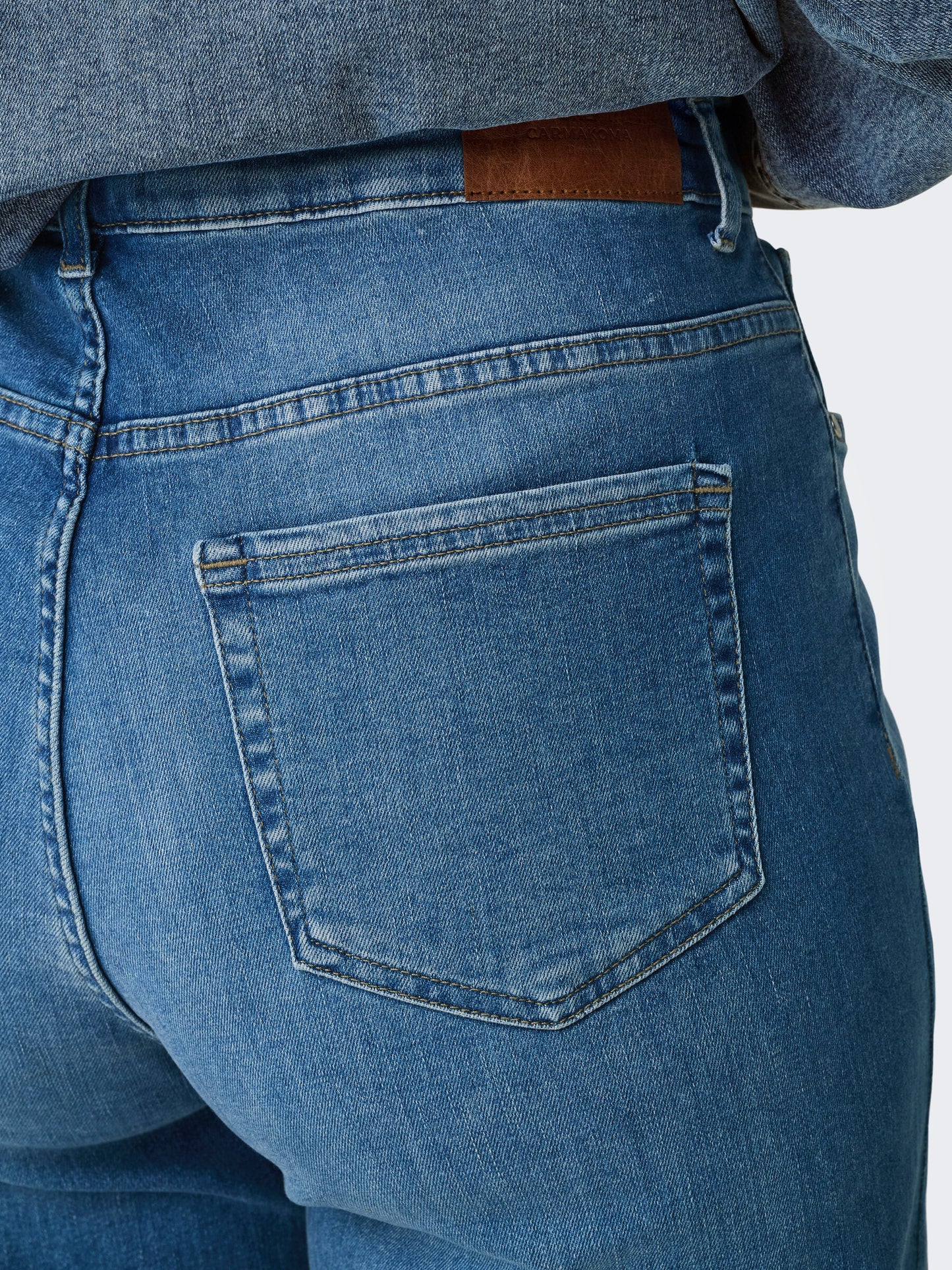 Nahaufnahme der Gesäßtaschen und Gürtelschlaufen der Only Carmakoma Carwilly wide fit Jeans in Medium blau. Perfekt für einen stilvollen Alltagslook.