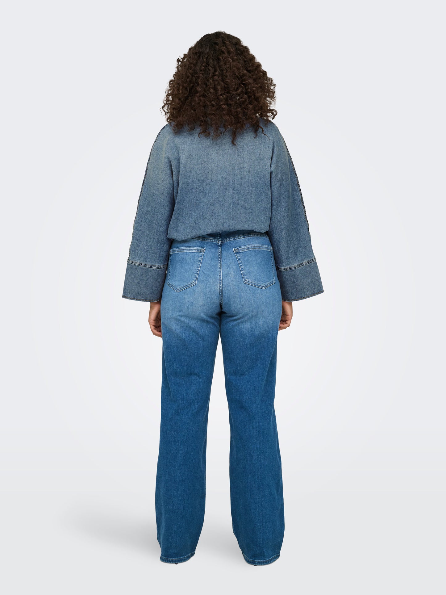 Ganzkörper-Rückansicht der Only Carmakoma Carwilly Wide Fit Jeans in medium blau. Vielseitiges Design mit schmeichelndem Schnitt, ideal für jeden Anlass.