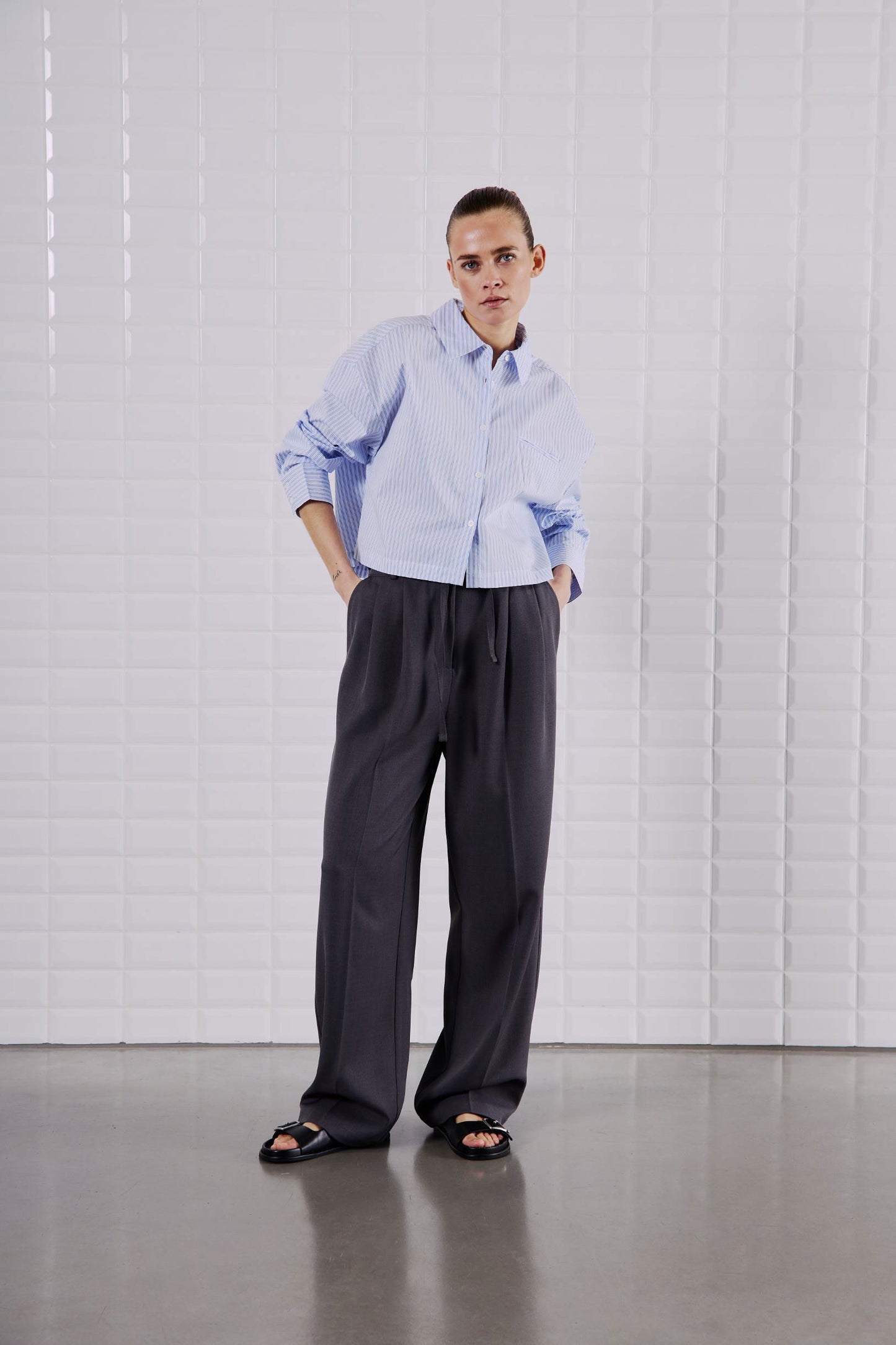 Frontansicht des WithBlack Quinie Cropped Shirt White Blue Stripe kombiniert mit weiter Hose für einen modernen Look.