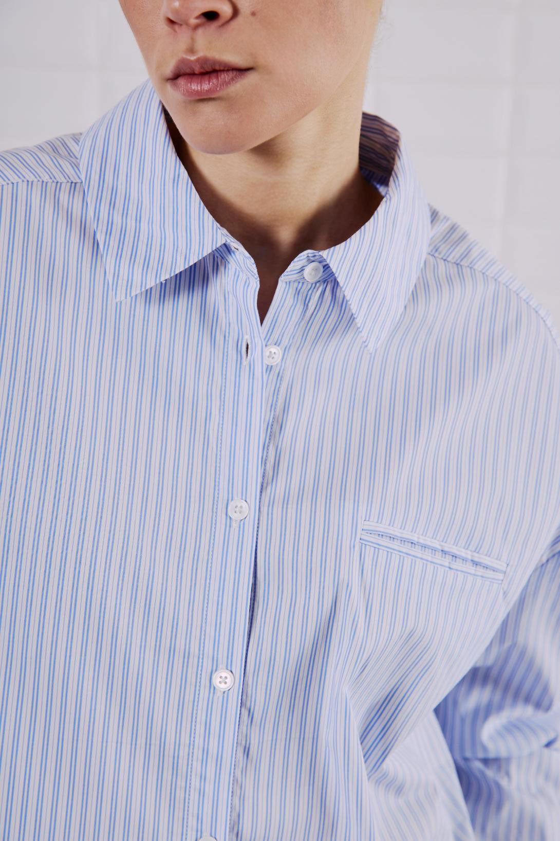 Nahaufnahme des WithBlack Quinie Cropped Shirt White Blue Stripe mit Brusttasche und Knopfleiste.