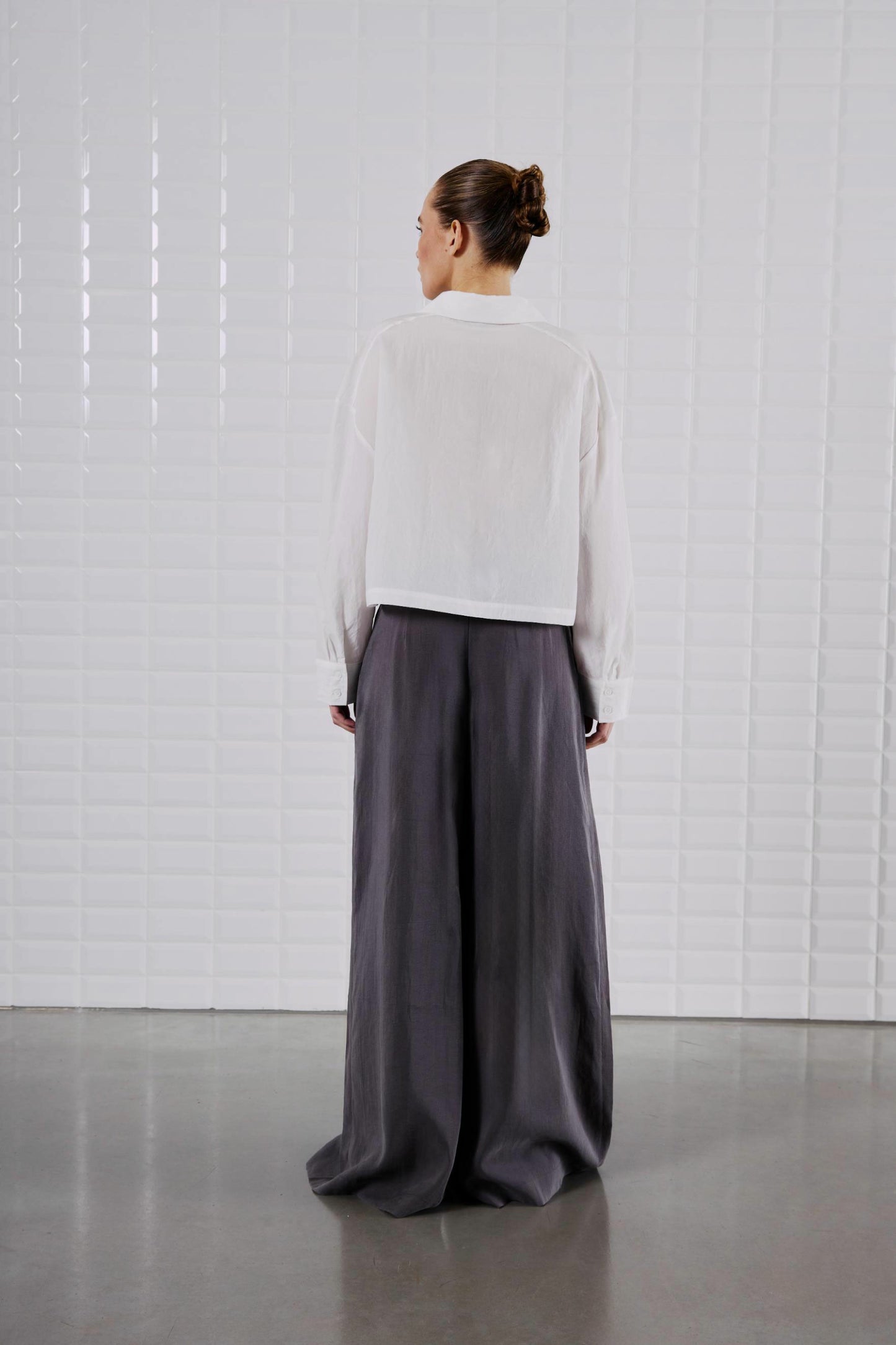 Rückansicht des WithBlack Quinie Cropped Shirt White, aus weicher Lyocell-Qualität, locker geschnitten und leicht transparent.