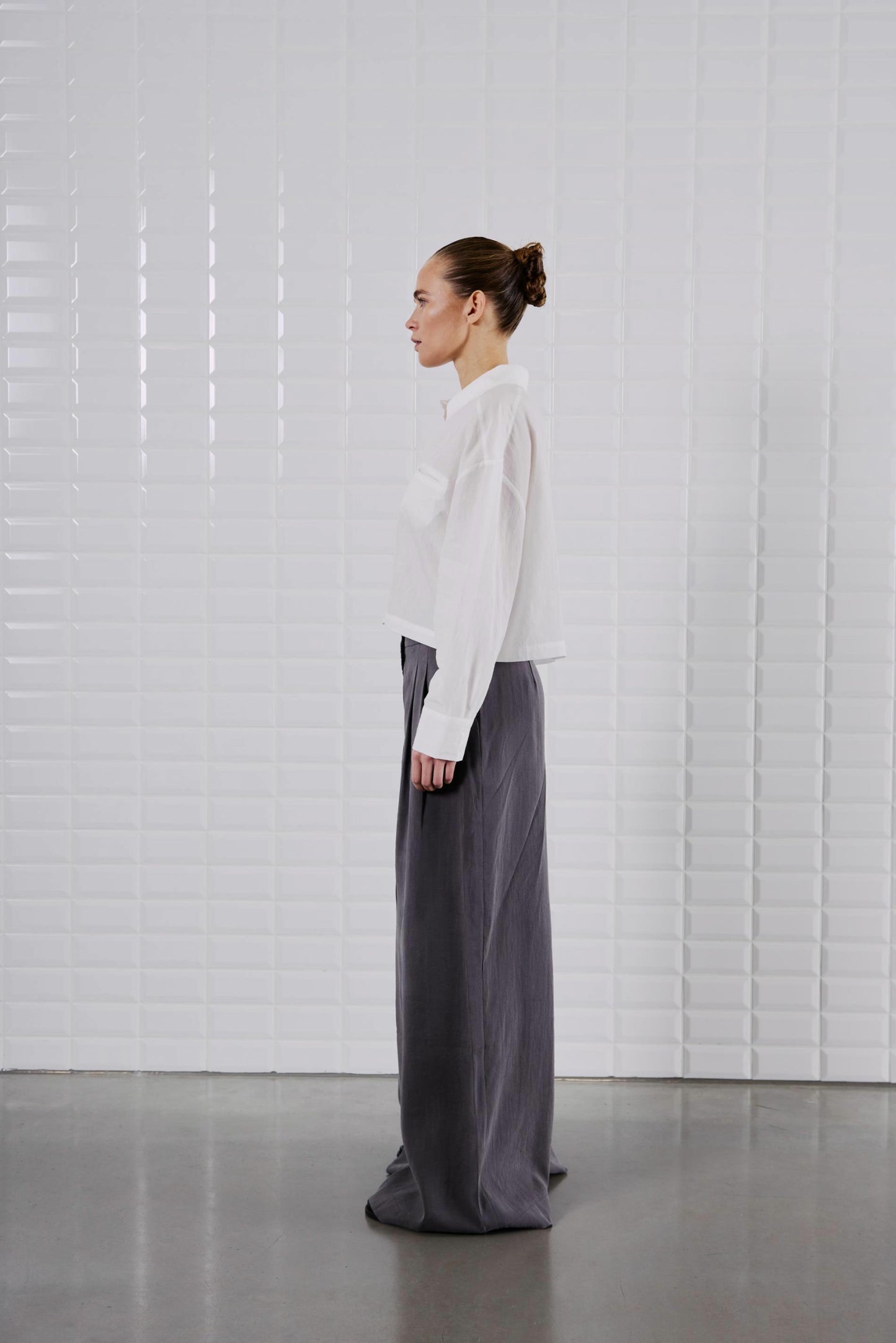 Seitenansicht des WithBlack Quinie Cropped Shirt White, zeigt die taillenlange Passform und die klassische Kragenform.