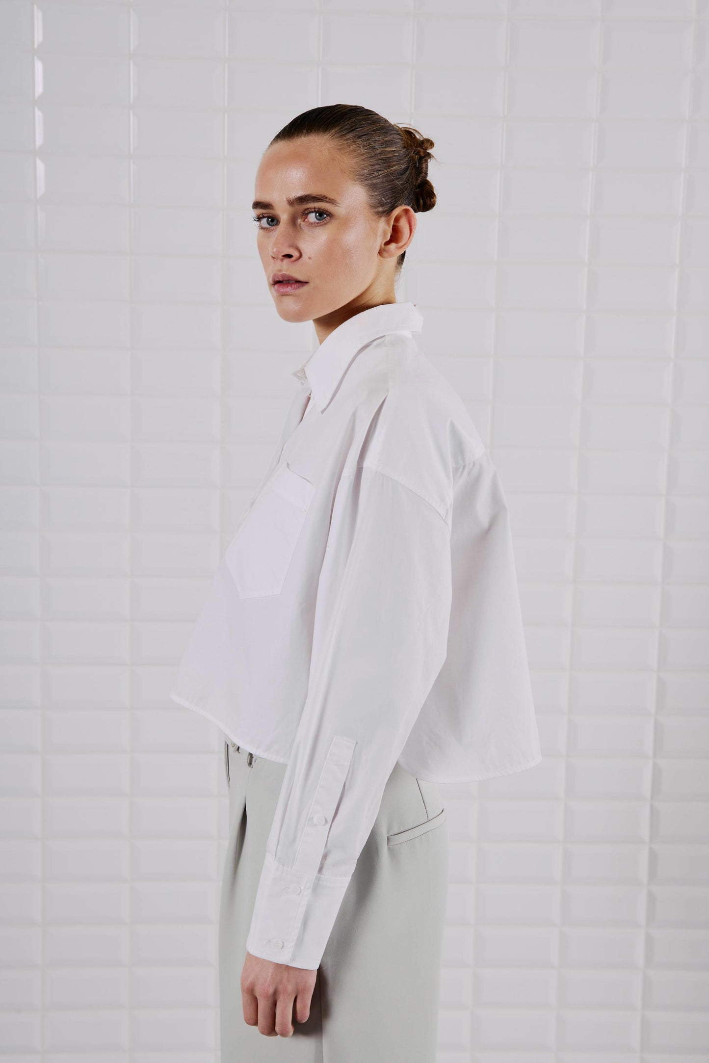 Seitenansicht des WithBlack Shorty Soft Cropped Shirt in Weiß mit Manschettenärmeln und klassischem Knopfverschluss.