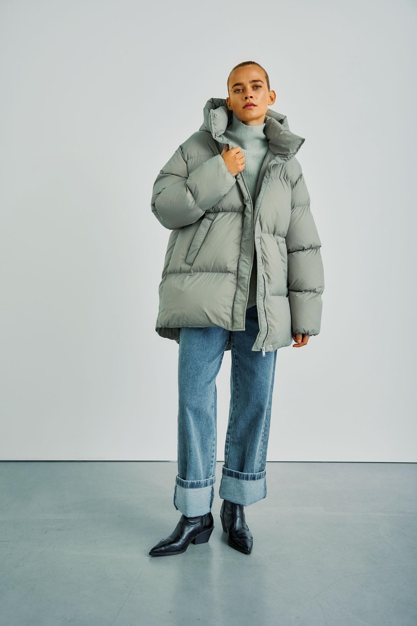 Frontansicht der WithBlack Vanessa Puffer Jacket in Ice Green, kombiniert mit einem Rollkragenpullover und lässigen Jeans.