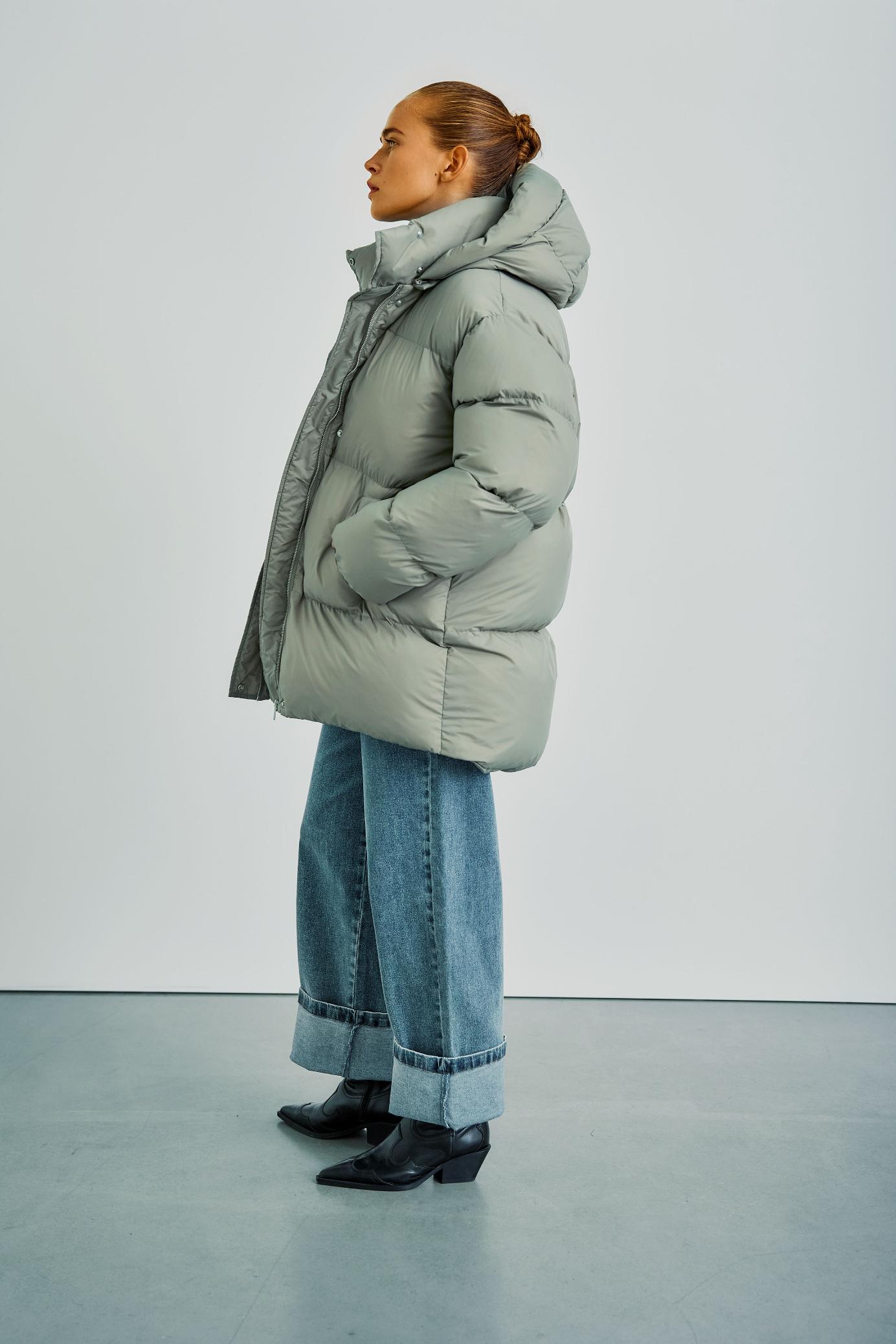 Seitliche Ansicht der WithBlack Vanessa Puffer Jacket in Ice Green, kombiniert mit lässigen Jeans und Stiefeletten.