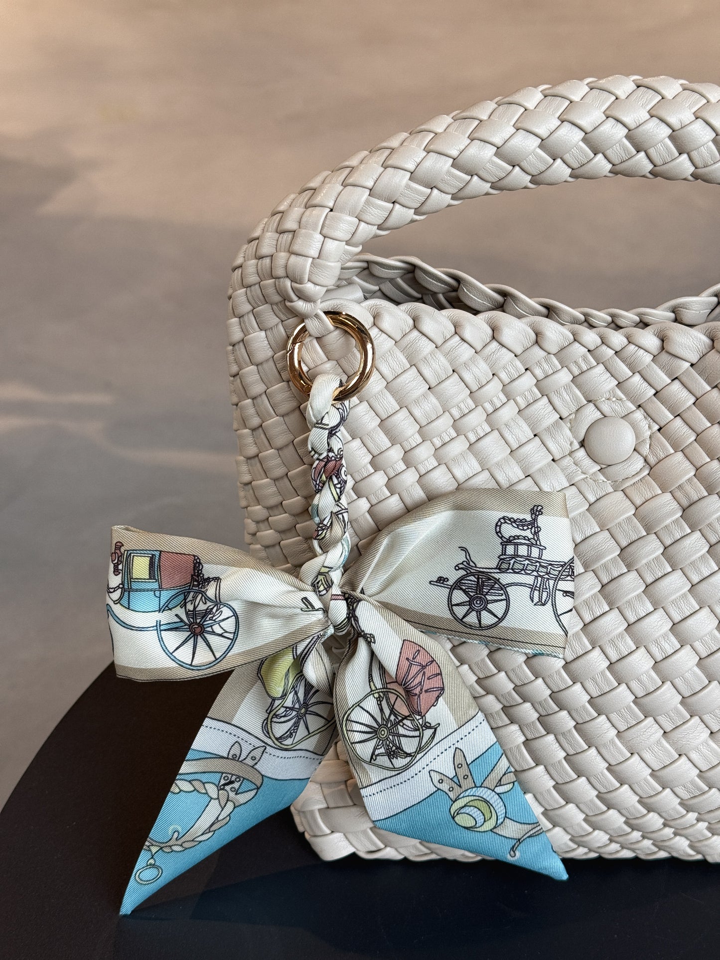 Braided Bow Charm in gedrehter Schleifenform, befestigt an einer Tasche – modischer Accessoire-Trend aus Twill in blauem Muster