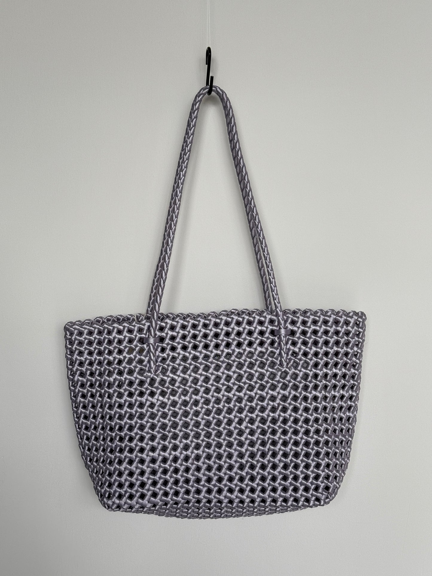 Geflochtene Braided Shopper Bag in Metallic-Lila mit langen Henkeln aus Stoff, an Haken aufgehängt