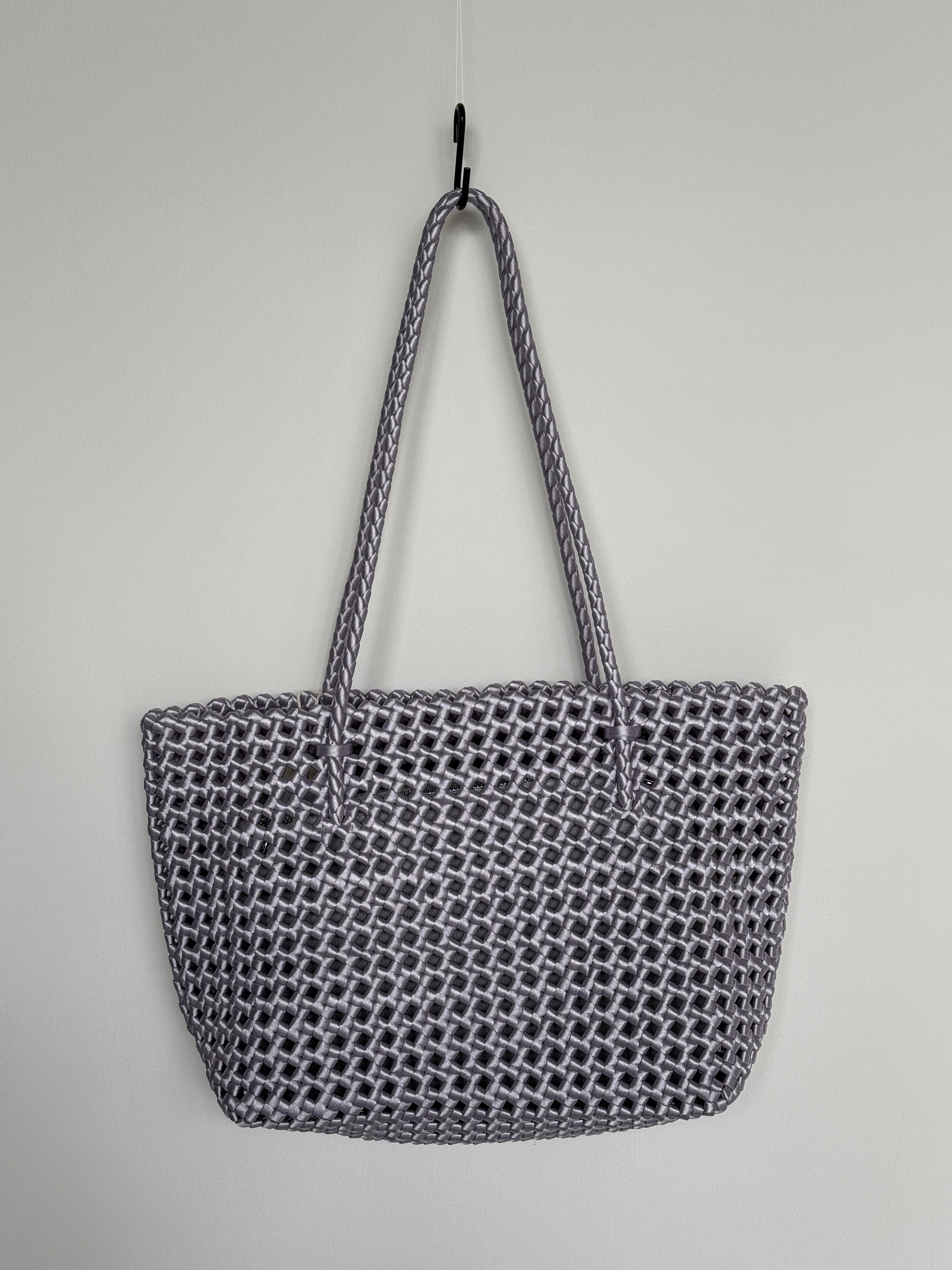 Geflochtene Braided Shopper Bag in Metallic-Lila mit langen Henkeln aus Stoff, an Haken aufgehängt