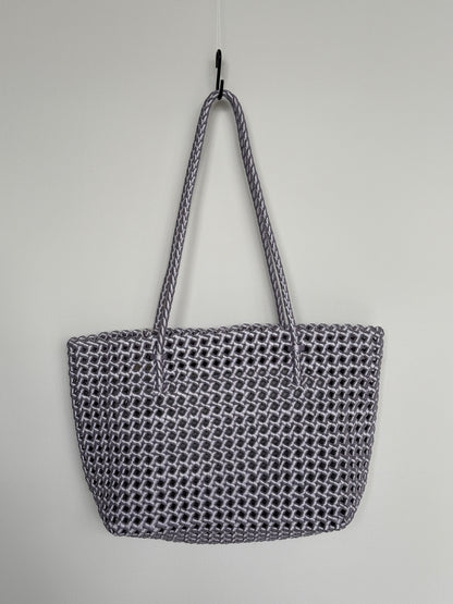 Geflochtene Braided Shopper Bag in Metallic-Lila mit langen Henkeln aus Stoff, an Haken aufgehängt