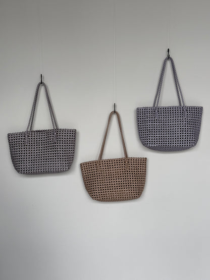 Drei Braided Shopper Bags in den Farben Silber, Gold und Flieder mit langem Henkel im geflochtenen Design an einer Wand hängend