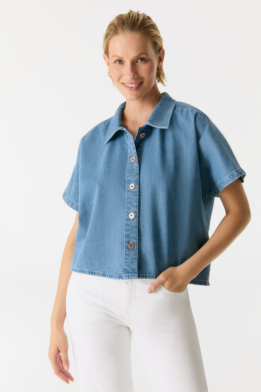 Vorderansicht des COJ Jennifer Relaxed Shirt in Medium Blue Denim, mit Knopfleiste und kurzem Schnitt, kombiniert mit weißer Jeans