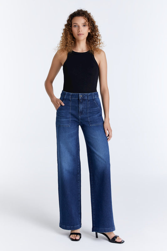 Gesamtansicht der COJ Lulu Wide Leg Dark Blue Jeans getragen von einer Frau, kombiniert mit einem schwarzen Oberteil und Sandalen.