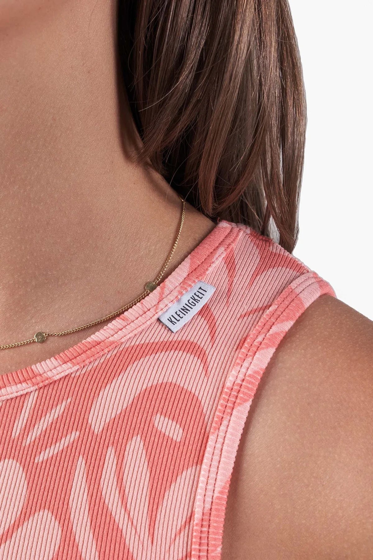 Nahaufnahme des Nackenbereichs vom Kleinigkeit Julia Toperts Vacay Peach Tanktop mit sichtbarem Kleinigkeit-Label – stilvolles Detail für den perfekten Sommerlook.