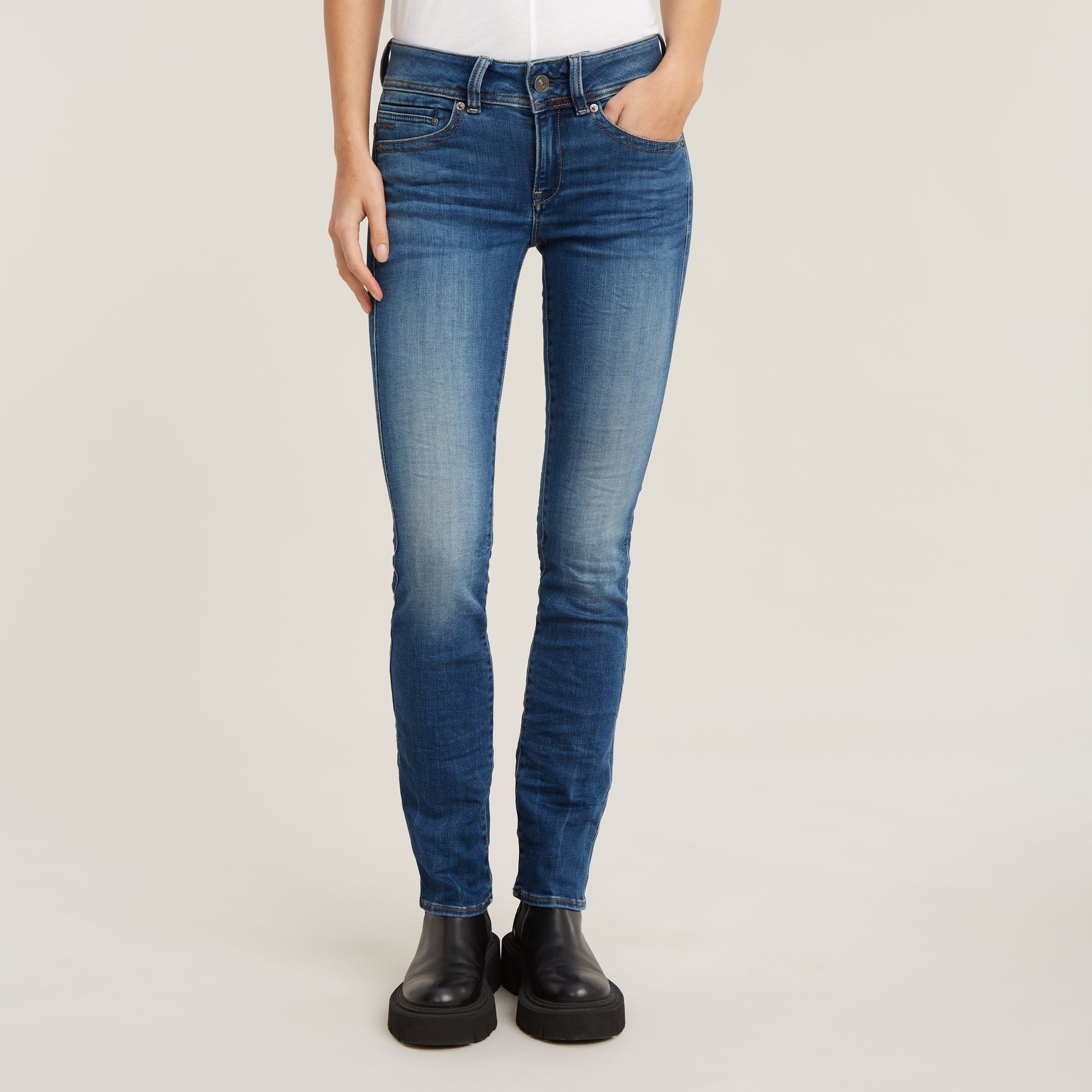 Frontalansicht der G-Star Midge Straight Jeans in Medium Indigo Aged, präsentiert mit minimalistischen schwarzen Boots.
