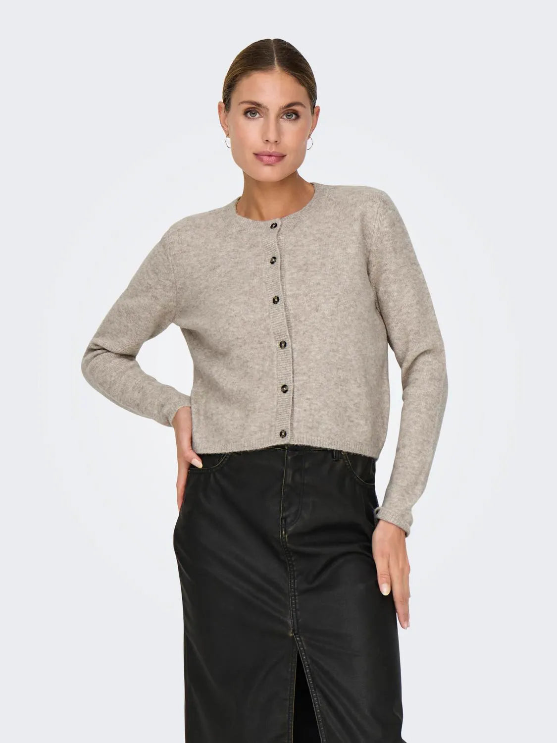 Model präsentiert einen beigen Strick-Cardigan von JDY, kombiniert mit einem schwarzen Rock für einen eleganten Look.