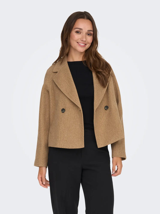 Frau kombiniert die JDY Viola Life Short Jacket Camel Melange mit schwarzer Hose für einen eleganten Look.