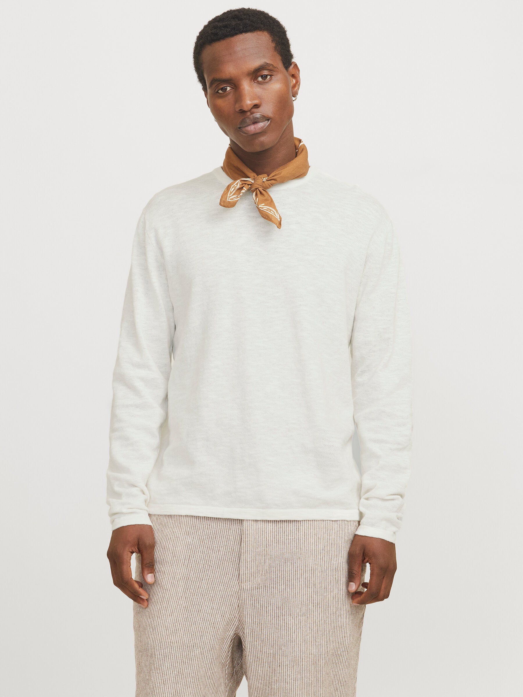 Jack & Jones Summer Knit Crew Neck Pullover in Weiß, getragen von einem Model mit braunem Halstuch und gestreifter Hose, in entspannter Frontansicht.