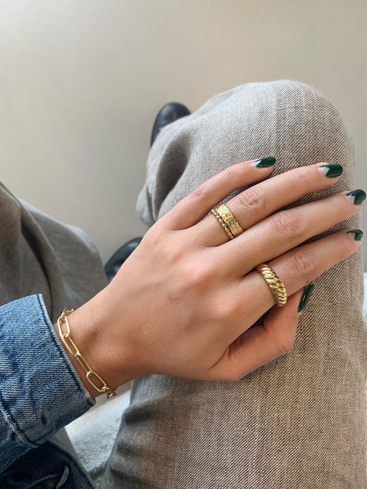 Nahaufnahme einer Hand, die das Jeberg Jewellery Sophia Chunk Armband trägt, kombiniert mit goldfarbenen Ringen, modischer Look.