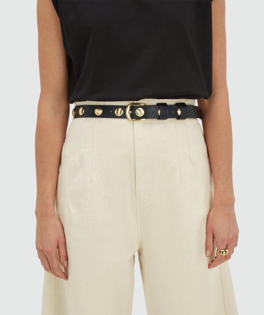 osh V Stella - Black Gürtel in Schwarz mit goldenen Nieten und Schnalle, Detailansicht an heller Hose getragen, modisches Accessoire für Damen