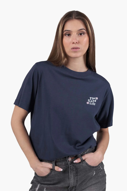 Model trägt das Kleinigkeit Enjoy the Flowers Shört Dark Blue von vorne – bequemes T-Shirt mit „The Good Life“ Stickerei auf der Brust, ideal für sommerliche Looks.