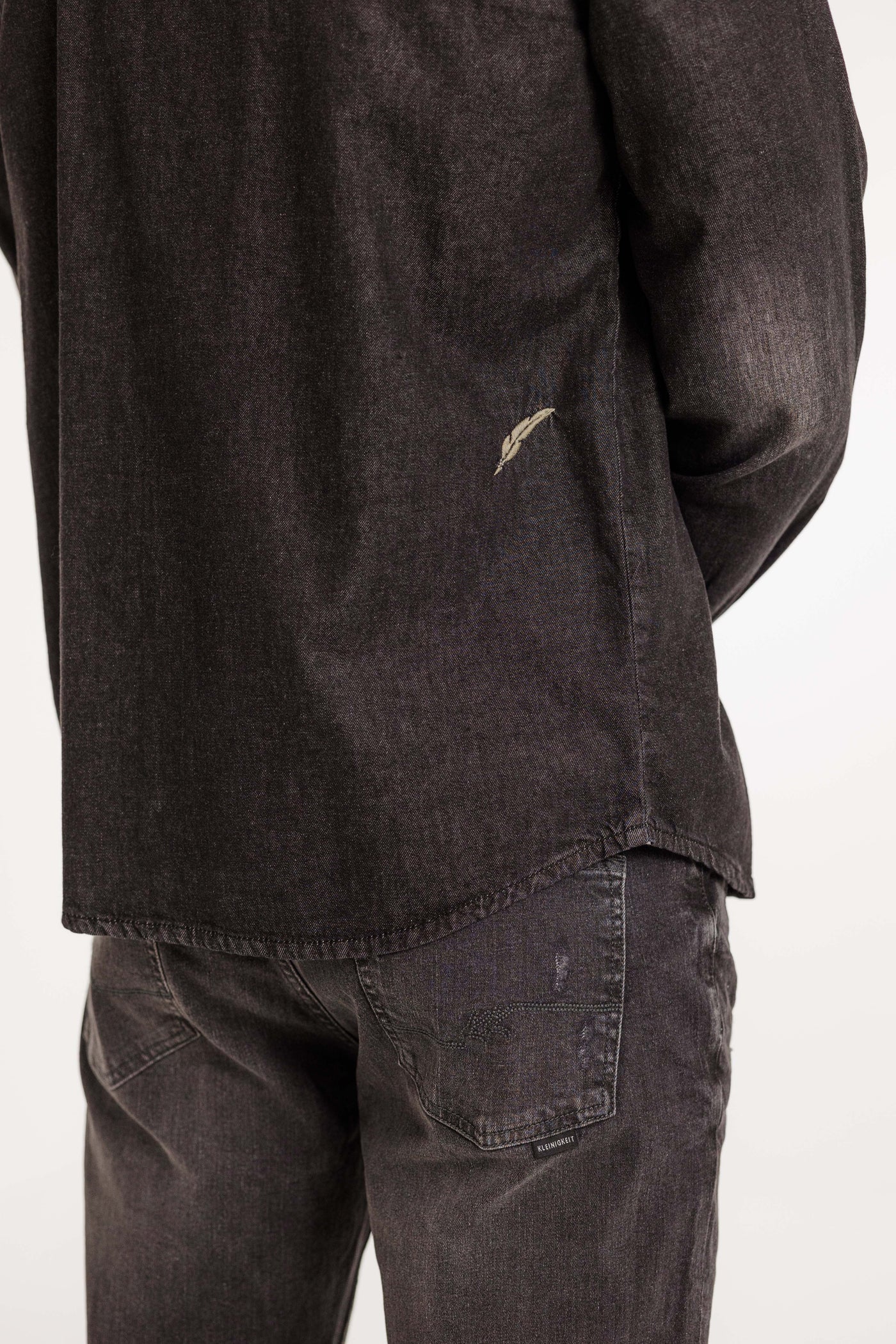 Rückansicht des Kleinigkeit Jürgen Jeansmann Overshirts in Grau. Mit dezenter Used-Optik und gestickter Feder am Rücken.
