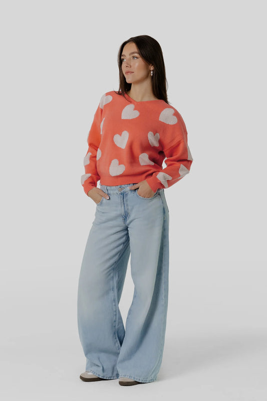 Vorderansicht des Kleinigkeit Lovely Wollma Pullovers mit süßen Herz-Details in leuchtendem Orange, kombiniert mit einer lockeren Jeans.