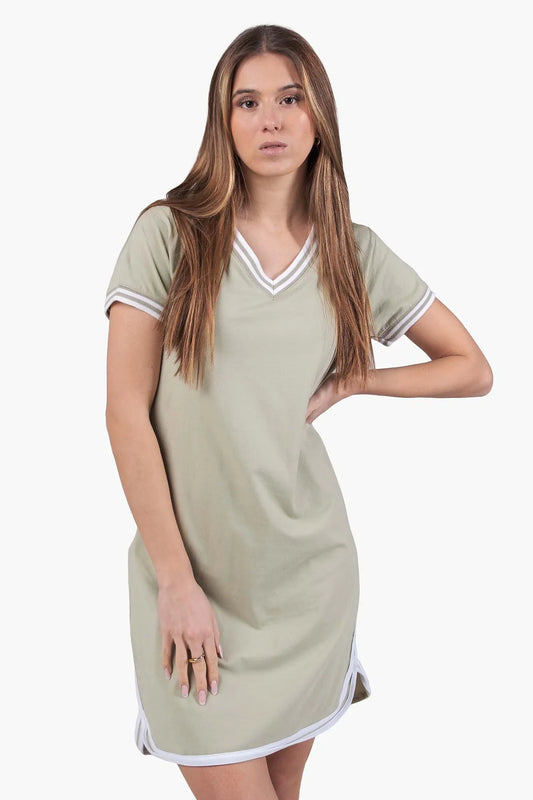 Frau trägt das Kleinigkeit Skörti V-Neck Sage Kleid – lässiges Sommerkleid in Salbeigrün mit sportlichem V-Ausschnitt, Poloärmeln und weißen Kontrastdetails, ideal für warme Tage.