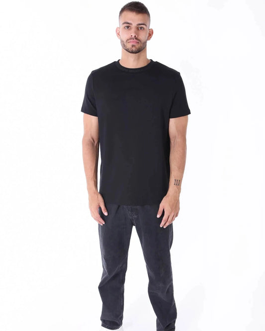 Ganzkörperansicht des Kleinigkeit Unterragendes Shörts in Schwarz, kombiniert mit Jeans und Sneakers. Lässiger Look mit hochwertiger Verarbeitung.
