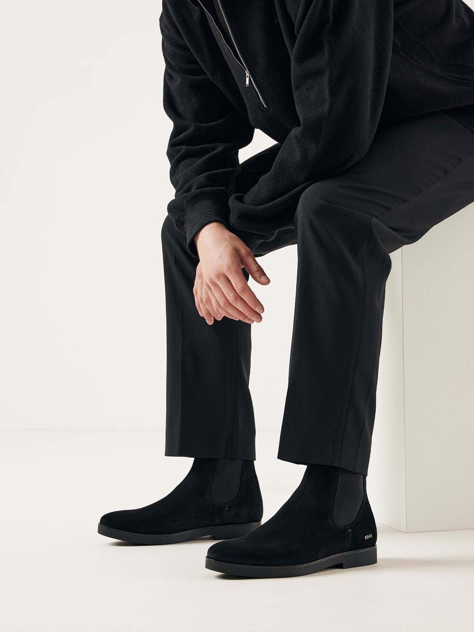 Person trägt die Nubbik Logan Chelsea Stiefel aus schwarzem Wildleder mit elegantem Outfit.