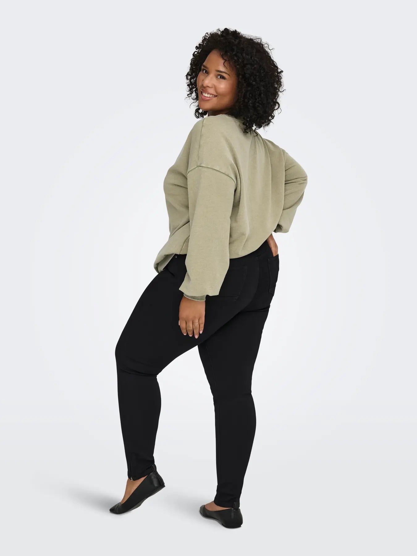 Only Carmakoma Karla Regular Waist Skinny Ankle Zip Black – Rückenansicht der schwarzen Jeans an Plus Size Model mit lockerem Sweatshirt